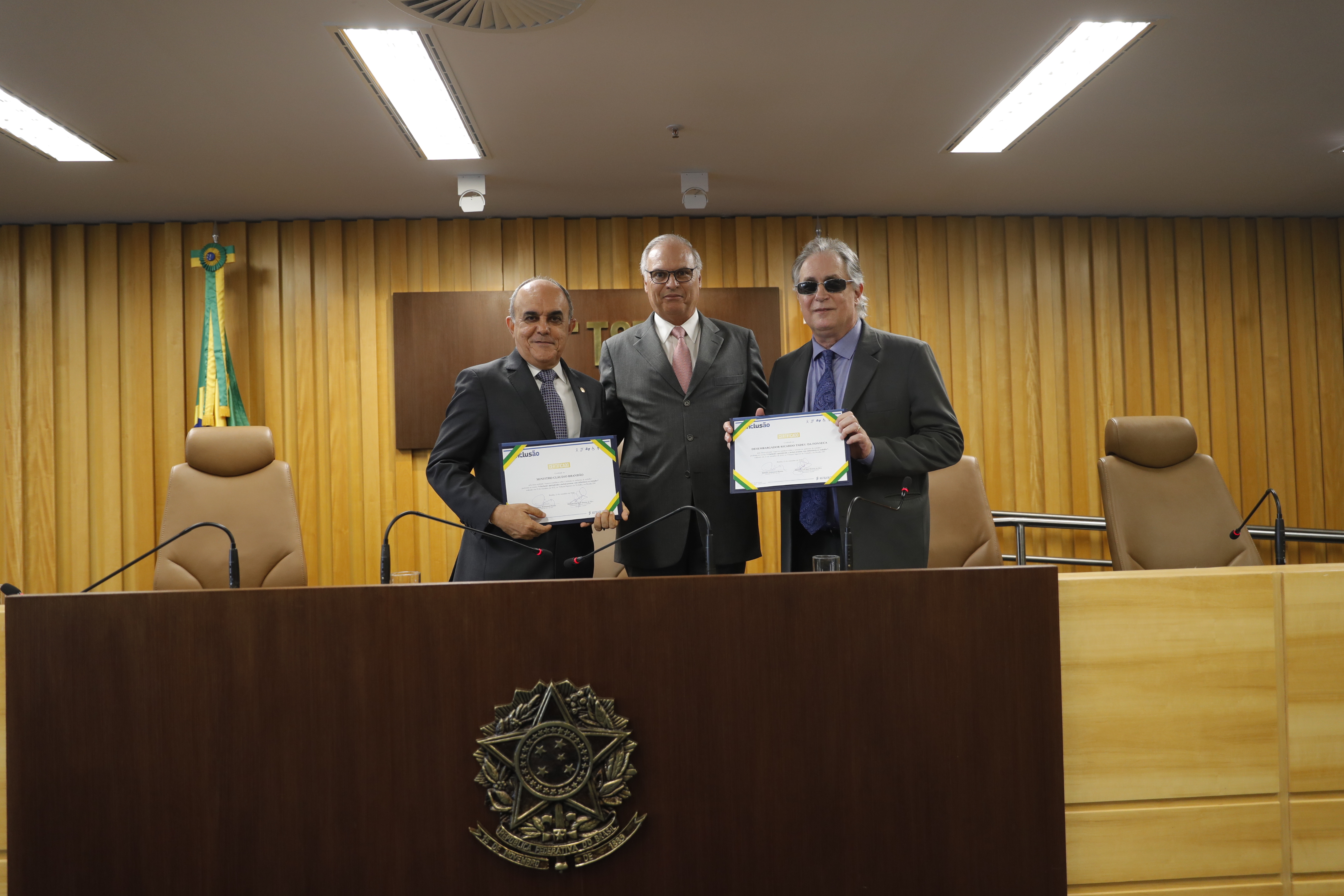 Ministro Cláudio Brandão, ministro Dezena e desembargador Ricardo Tadeu posam para foto com o certificado do evento